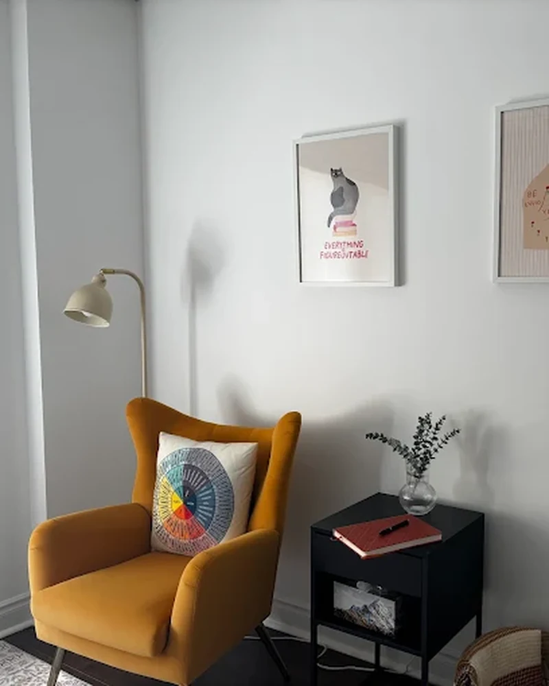 Consulting nook at Clear Moon Therapy — yellow wingback chair, floor lamp, and wall art